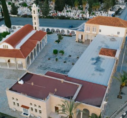 Stunning aerial view of a church with red roof in an urban setting surrounded by greenery.